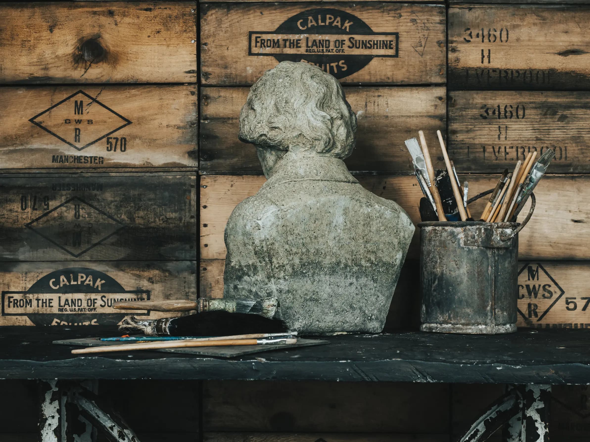 Statue and painting brushes on table back